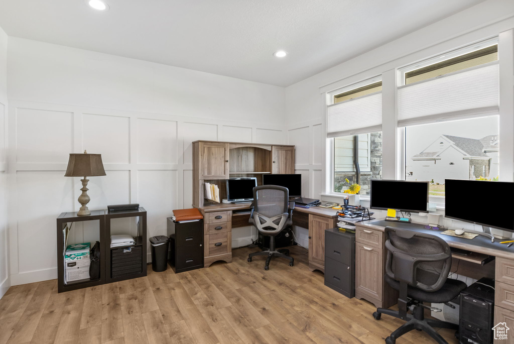 Office space featuring a decorative wall, light wood finished floors, and recessed lighting