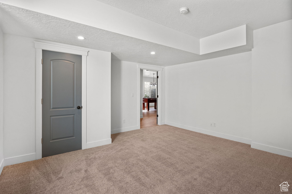 Below grade area featuring a textured ceiling, carpet floors, baseboards, and recessed lighting