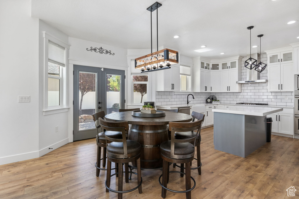 Kitchen with a center island, tasteful backsplash, light wood-style floors, glass insert cabinets, and gas cooktop