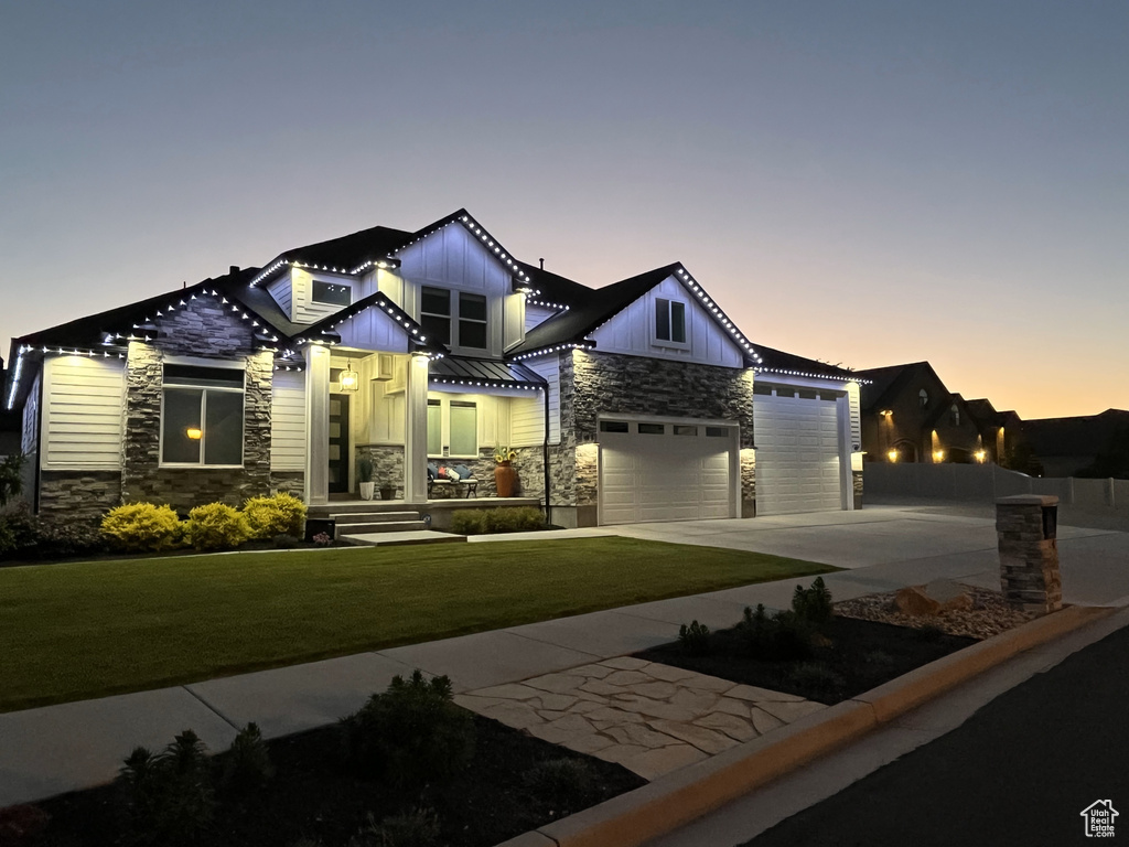 View of front of property with stone siding, board and batten siding, driveway, and an attached garage
