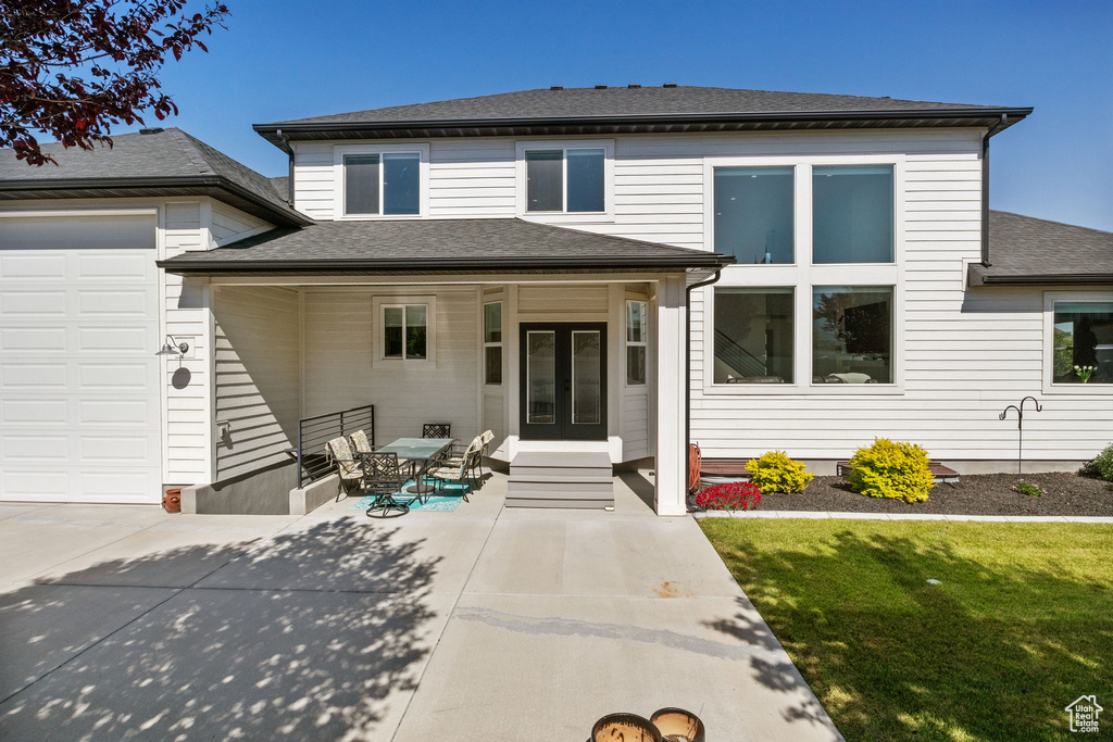 View of front of home featuring french doors, roof with shingles, and a front lawn