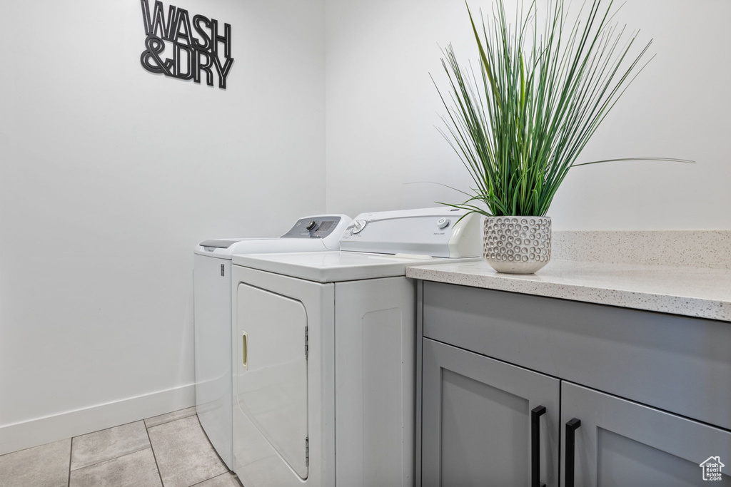 Laundry room with washer and clothes dryer, baseboards, light tile patterned floors, and cabinet space