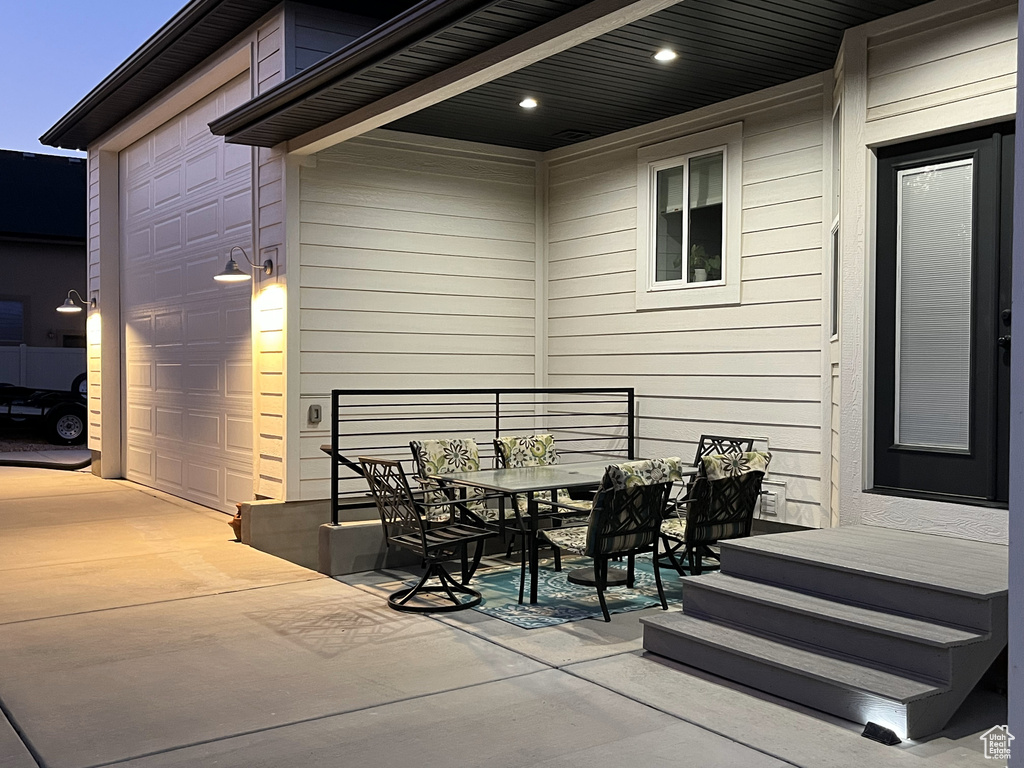 View of patio / terrace featuring outdoor dining space, a garage, and driveway