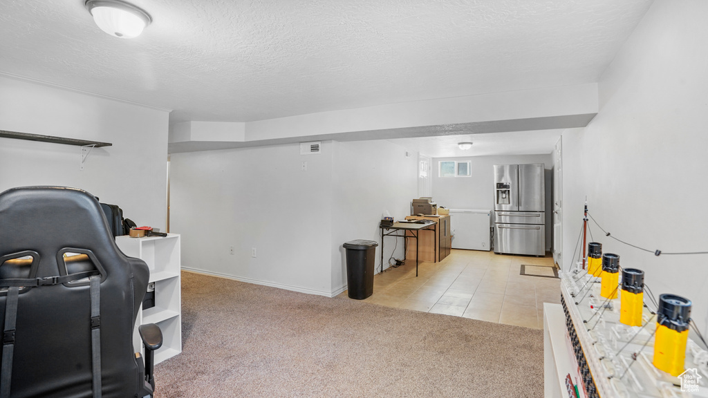 Rec room with light carpet, a textured ceiling, and light tile patterned floors