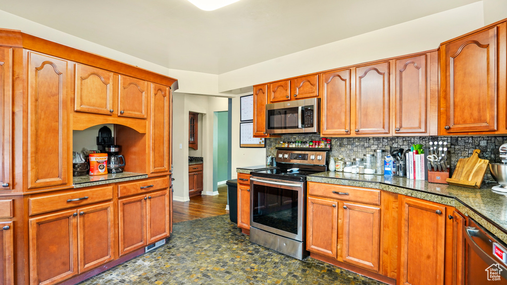 Kitchen featuring stainless steel appliances, tasteful backsplash, and brown cabinetry