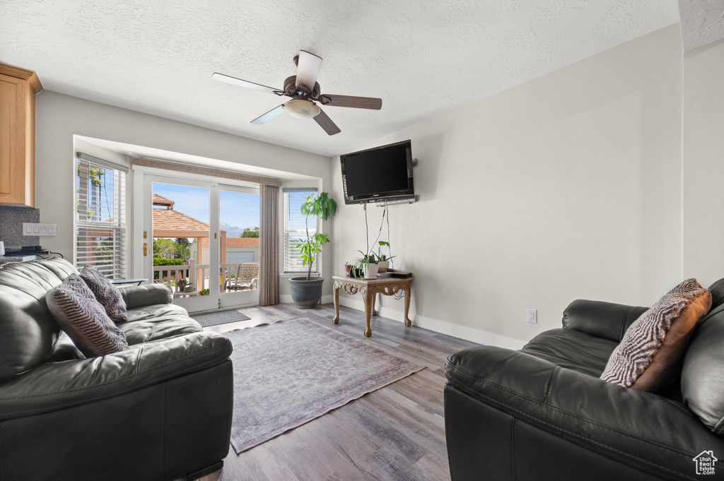 Living area featuring a ceiling fan, wood finished floors, a textured ceiling, and baseboards