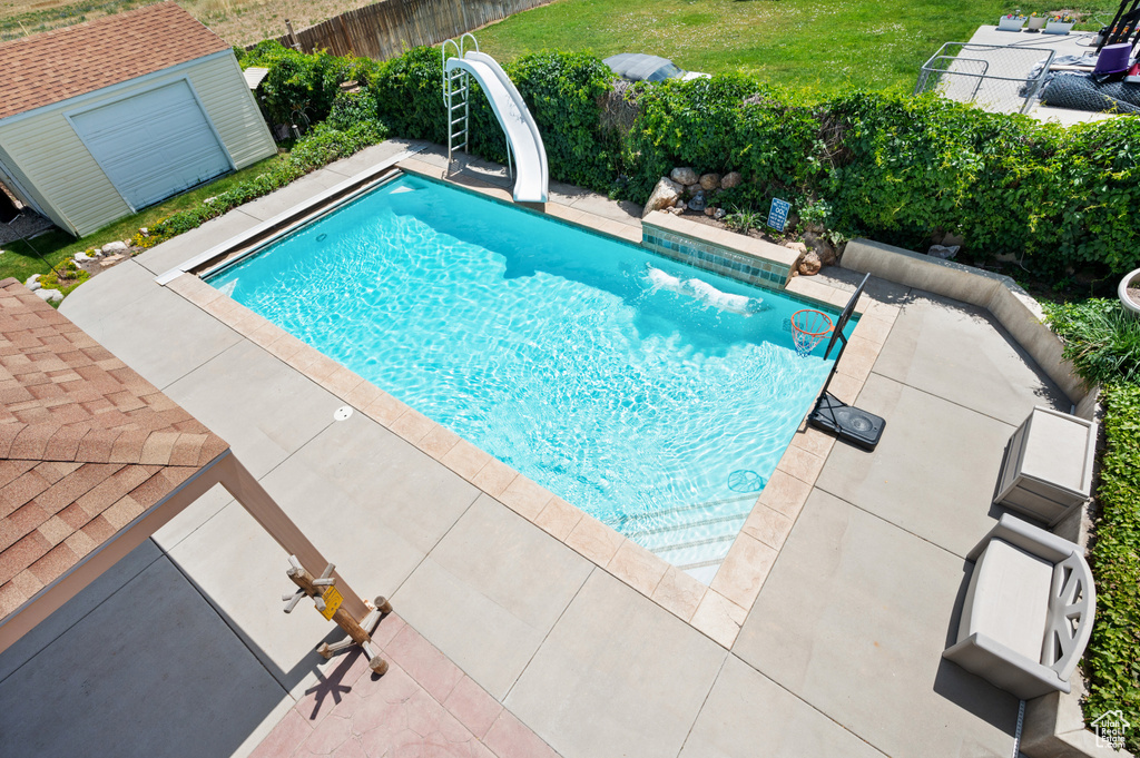 View of swimming pool featuring a water slide, a fenced backyard, and a patio