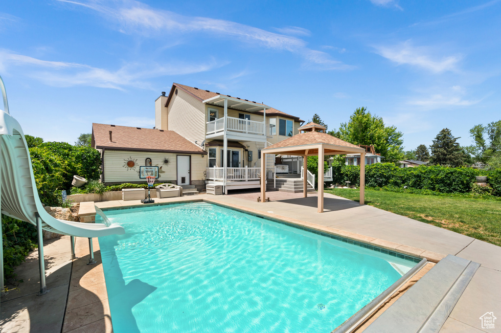 View of pool featuring a water slide, a gazebo, a patio area, and a lawn