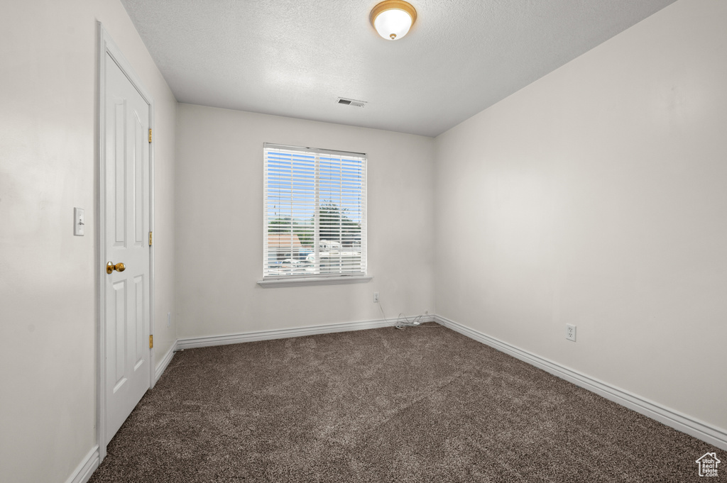 Carpeted spare room featuring baseboards and a textured ceiling