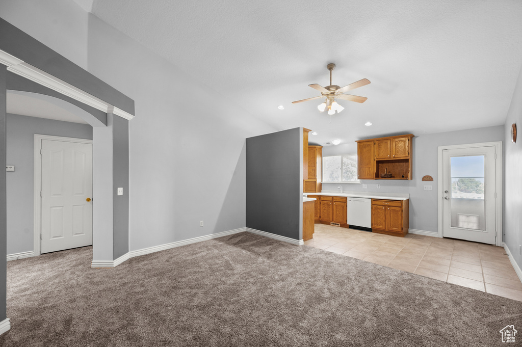 Unfurnished living room featuring light colored carpet, a ceiling fan, baseboards, arched walkways, and light tile patterned floors