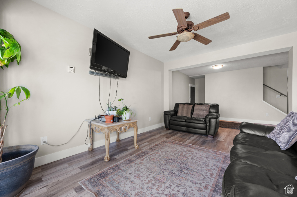 Living area with a ceiling fan, wood finished floors, and baseboards