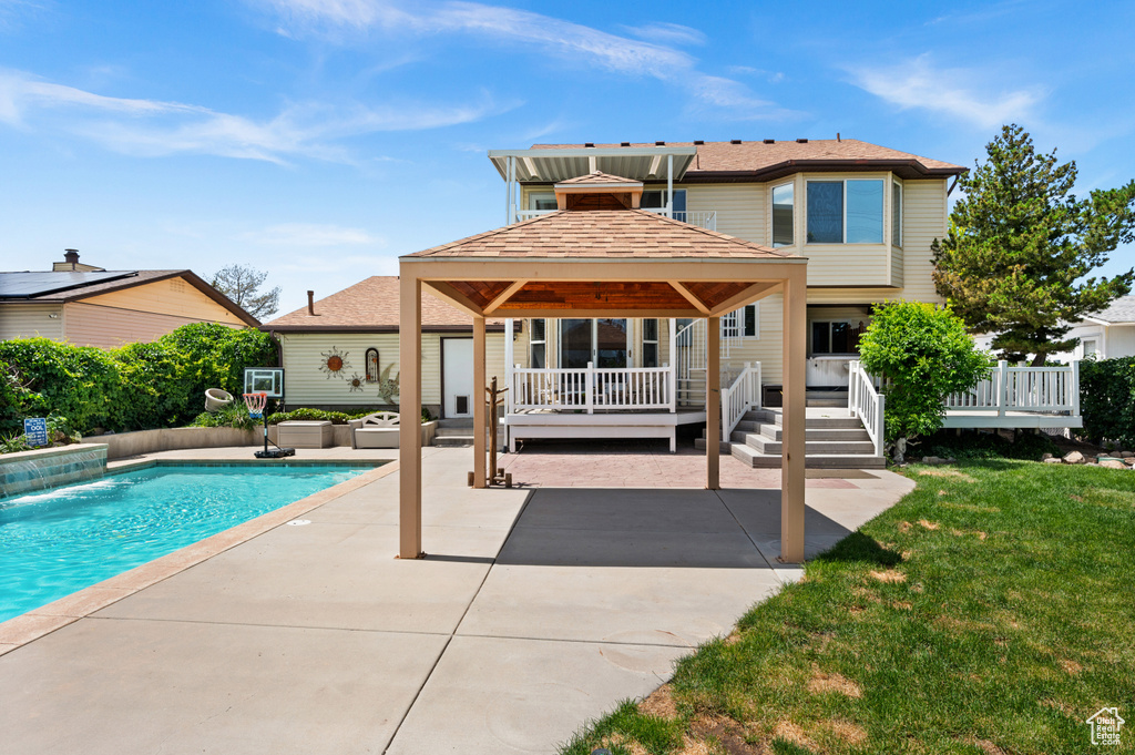 Rear view of property featuring a gazebo, a patio area, a wooden deck, an outdoor pool, and a yard
