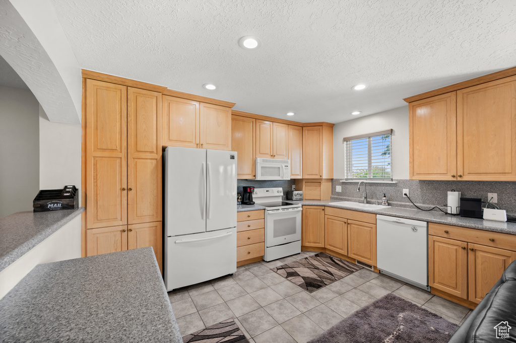 Kitchen with white appliances, a sink, tasteful backsplash, recessed lighting, and a textured ceiling
