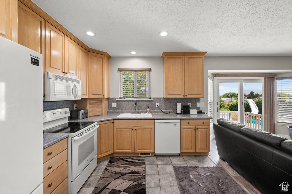 Kitchen featuring white appliances, a sink, tasteful backsplash, healthy amount of natural light, and recessed lighting