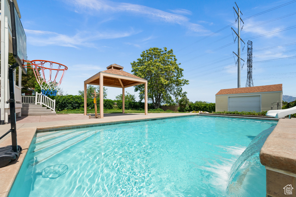 Outdoor pool with a water slide, a gazebo, and a patio