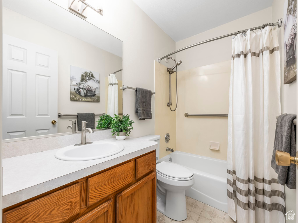 Bathroom with vanity, shower / tub combo with curtain, and toilet