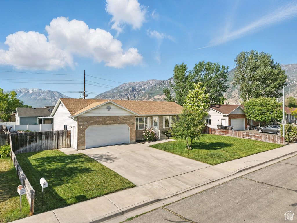 Ranch-style house with a mountain view, a garage, concrete driveway, and brick siding