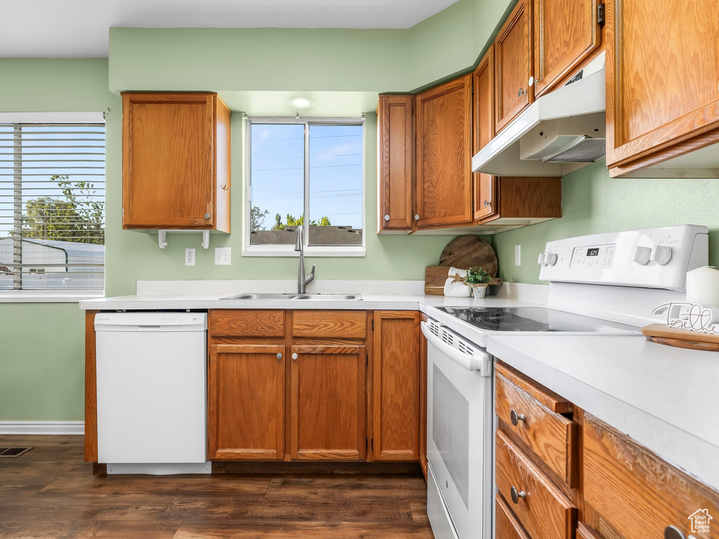 Kitchen featuring white appliances, under cabinet range hood, a sink, and plenty of natural light