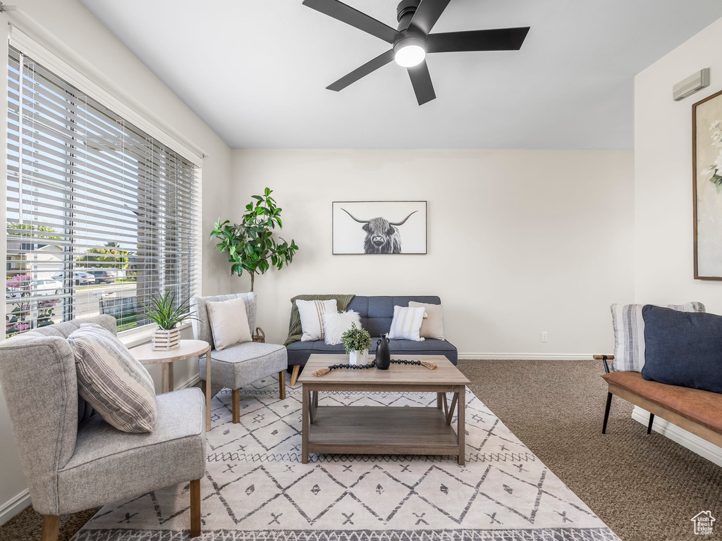 Living area with a ceiling fan, healthy amount of natural light, baseboards, and carpet