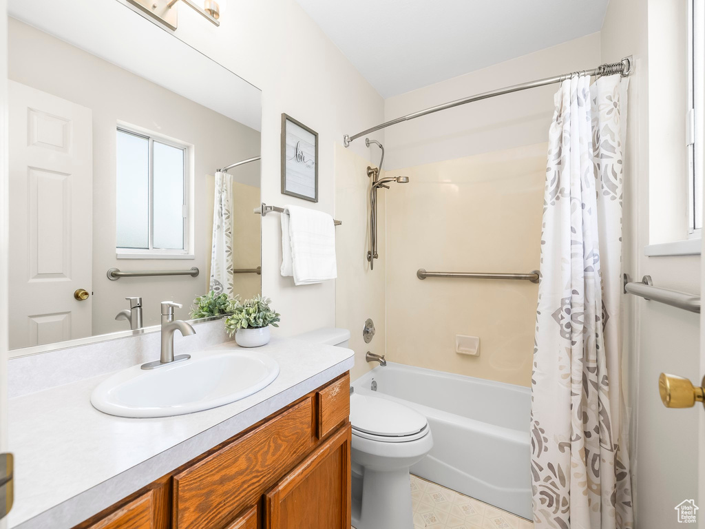 Full bathroom featuring vanity, shower / tub combo with curtain, and toilet