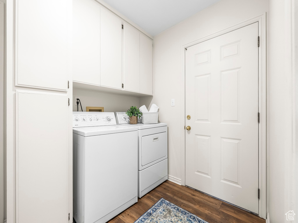 Washroom featuring washer and clothes dryer, cabinet space, and dark wood-style floors