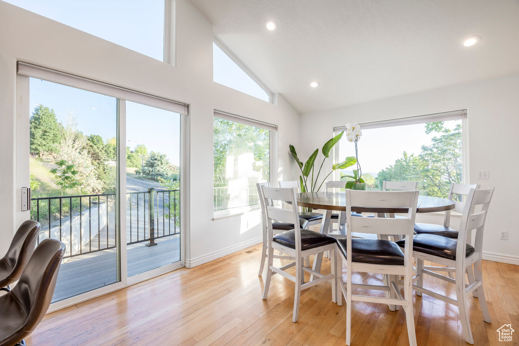 Dining area with healthy amount of natural light, baseboards, light wood-style floors, recessed lighting, and high vaulted ceiling