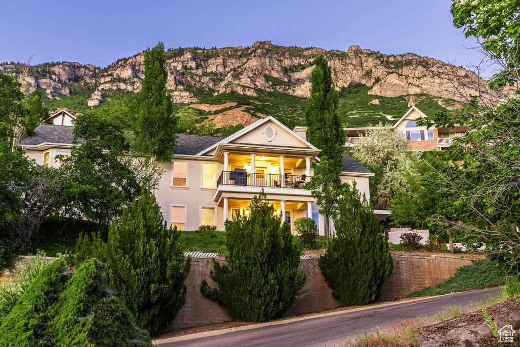 View of front of home featuring a balcony, a mountain view, a chimney, and stucco siding