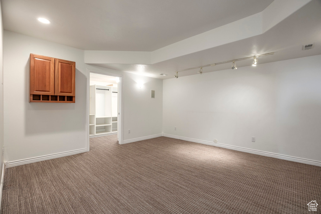 Carpeted spare room with rail lighting and baseboards