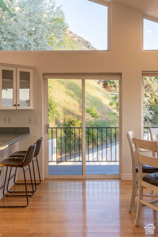 Dining area with wood finished floors, baseboards, healthy amount of natural light, and a towering ceiling