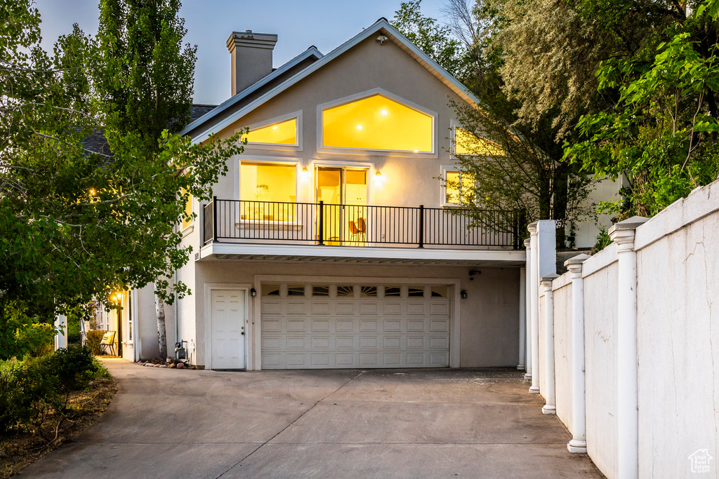 View of front of home with a balcony, driveway, stucco siding, and a garage