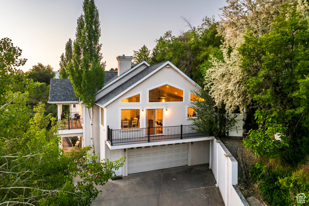 View of front of property with stucco siding, a chimney, concrete driveway, and an attached garage