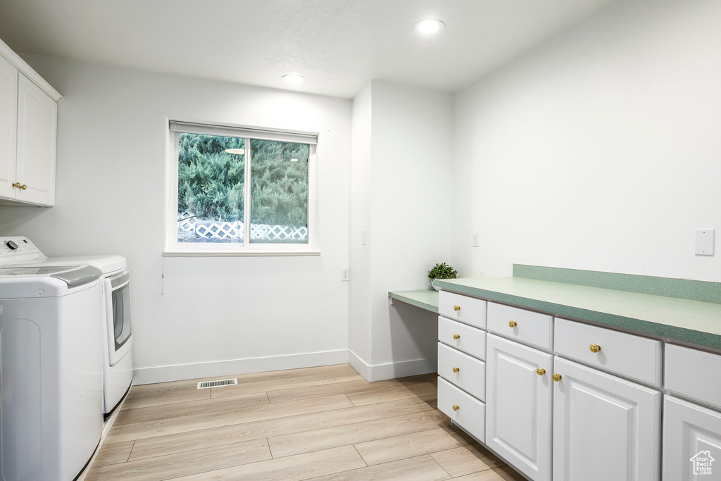 Washroom featuring independent washer and dryer, cabinet space, light wood-style flooring, recessed lighting, and baseboards