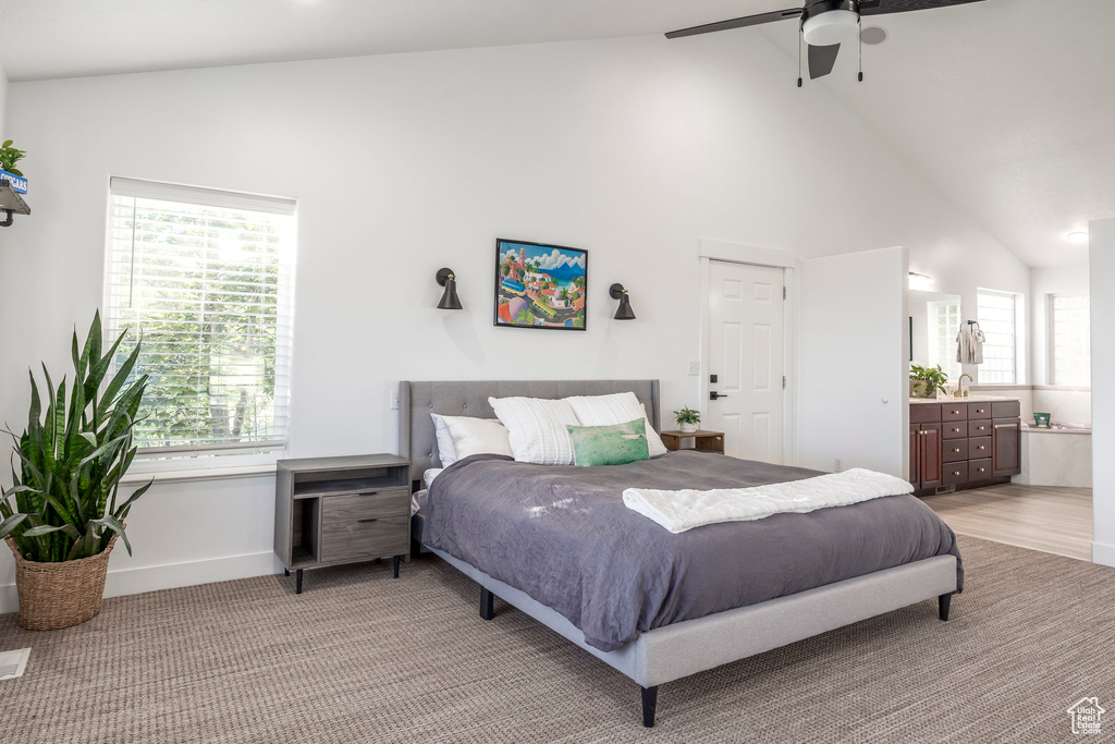 Bedroom featuring high vaulted ceiling, connected bathroom, baseboards, light colored carpet, and a ceiling fan