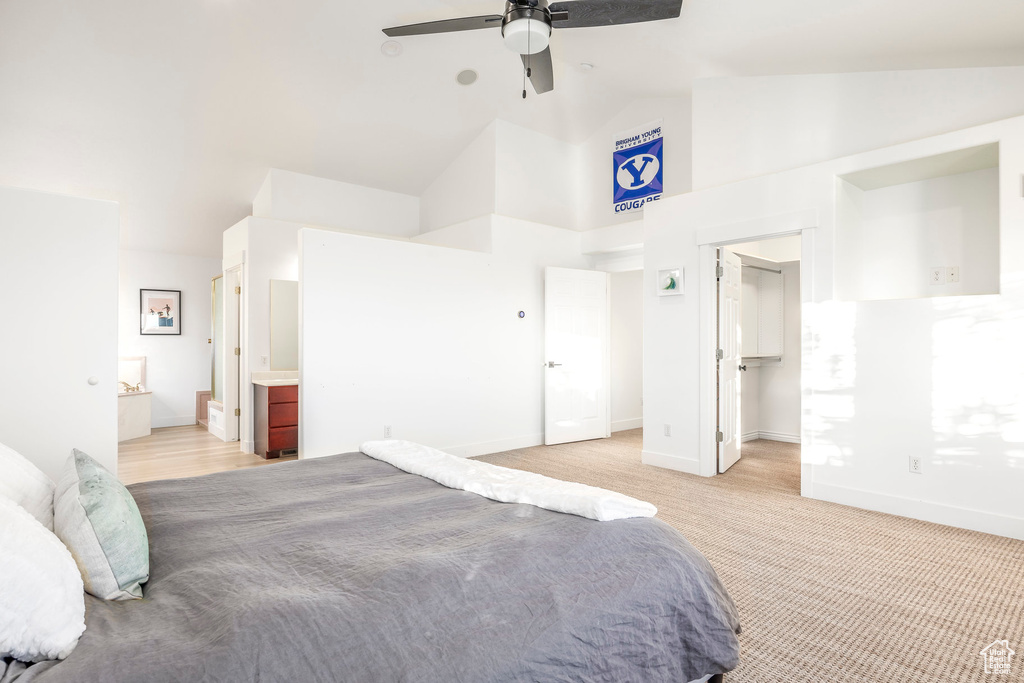 Bedroom featuring high vaulted ceiling, baseboards, a walk in closet, ensuite bathroom, and a ceiling fan