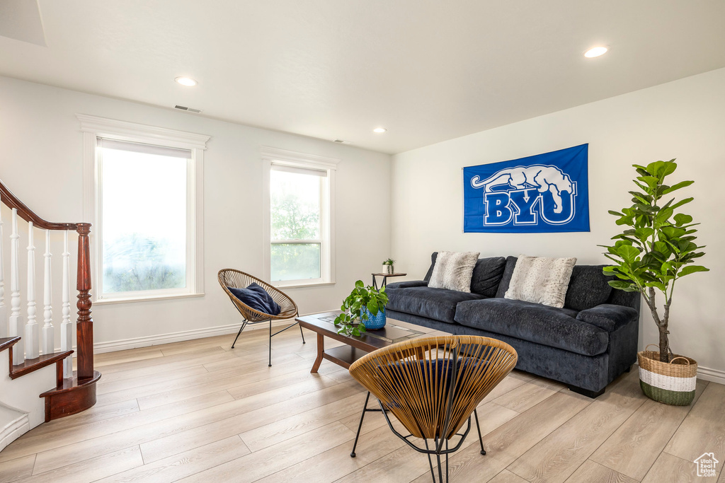 Living room with stairs, light wood-type flooring, baseboards, and recessed lighting
