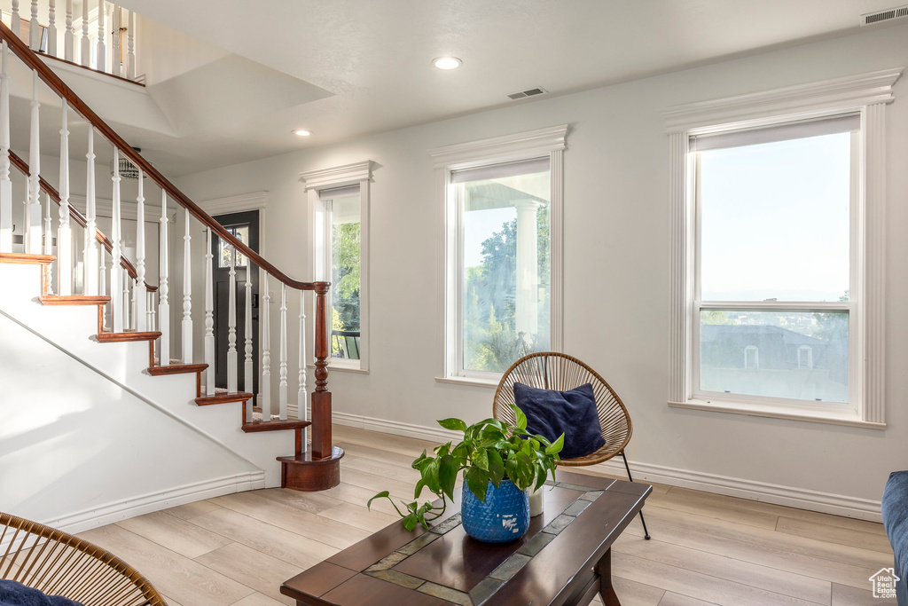Living room with light wood finished floors, baseboards, stairway, and recessed lighting