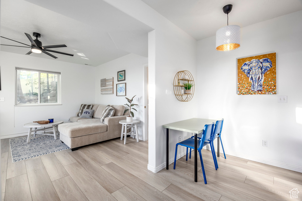 Living area featuring light wood-style floors, a ceiling fan, and baseboards