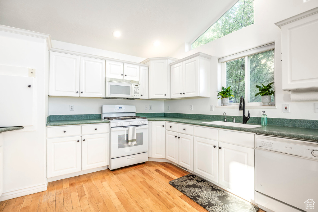 Kitchen featuring white appliances, a sink, light wood-type flooring, white cabinets, and recessed lighting
