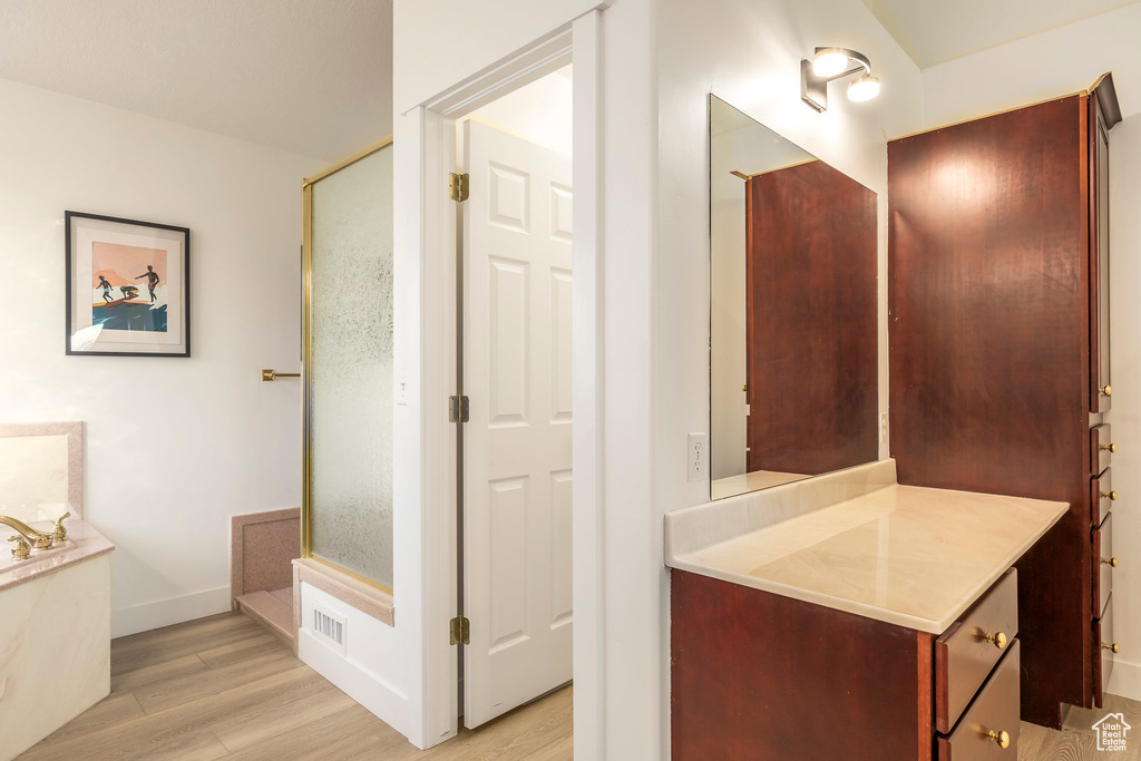 Bathroom featuring wood finished floors, vanity, a garden tub, and baseboards
