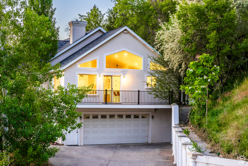 View of front of property featuring stucco siding, driveway, an attached garage, and a balcony