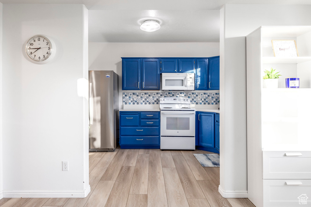 Kitchen with white appliances, blue cabinets, light countertops, and light wood-style floors