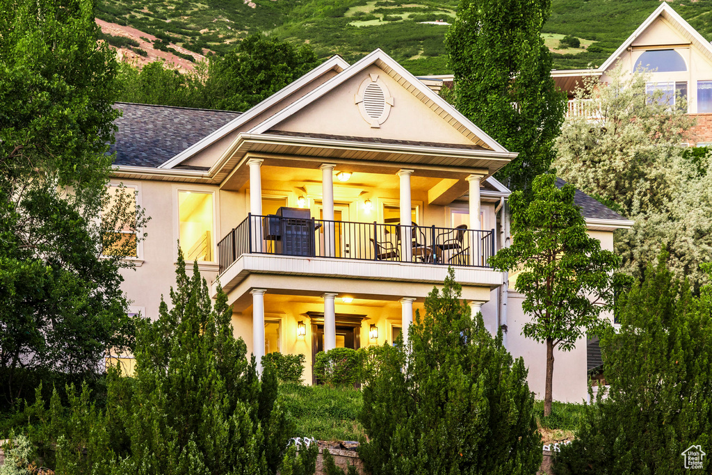 Back of property with a balcony, stucco siding, and a shingled roof