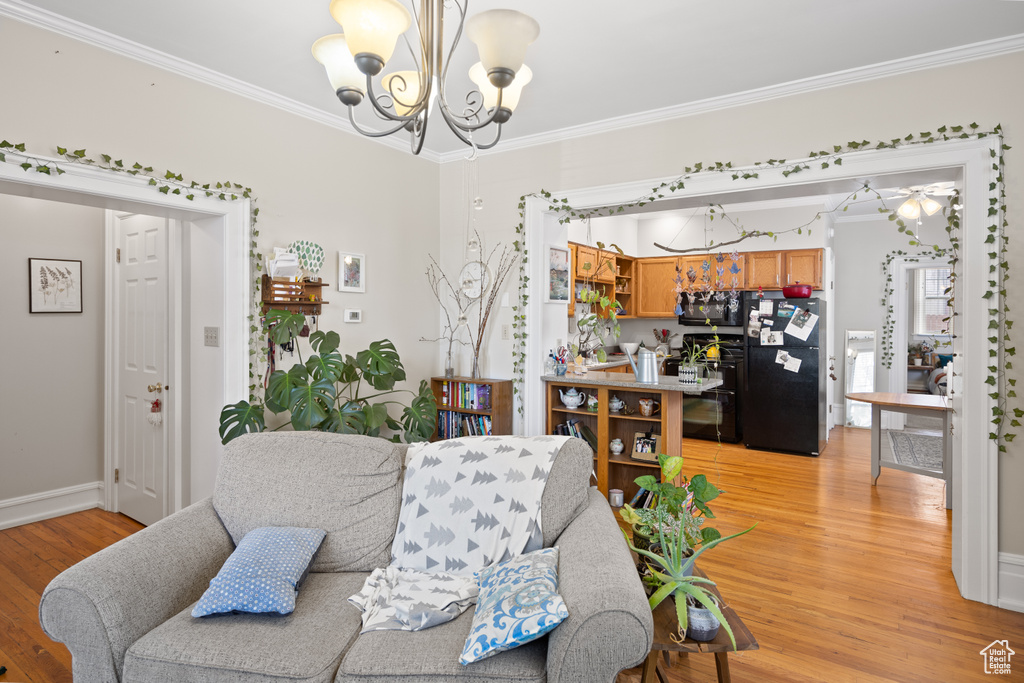 Living area featuring a chandelier, crown molding, light wood-type flooring, and baseboards