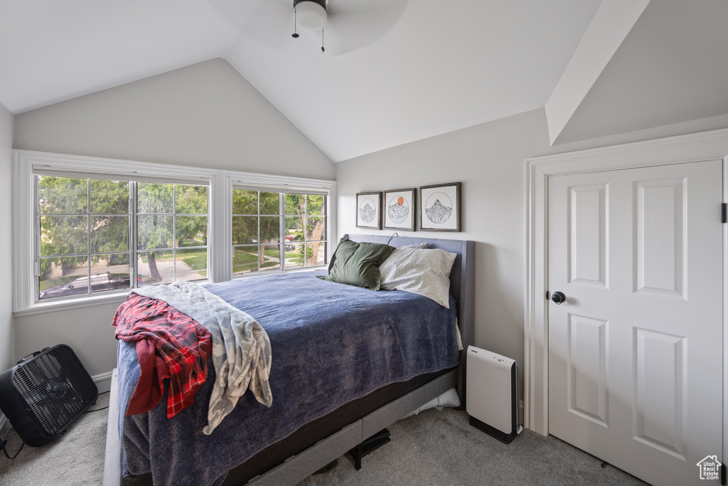 Bedroom with carpet flooring, vaulted ceiling, multiple windows, and ceiling fan