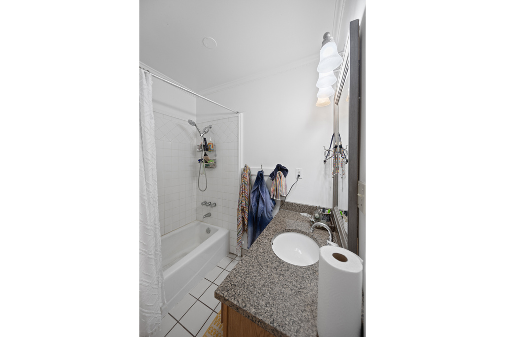 Bathroom featuring vanity, shower / bath combination with curtain, tile patterned floors, and ornamental molding