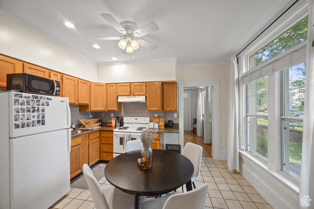 Kitchen featuring white appliances, healthy amount of natural light, light tile patterned floors, ornamental molding, and recessed lighting