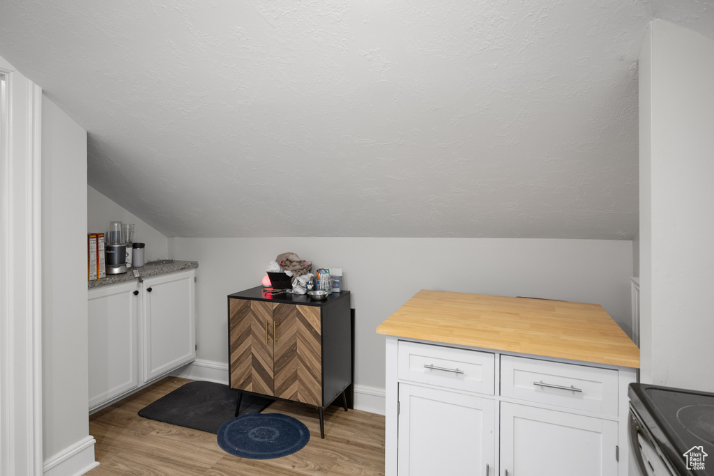 Bar with lofted ceiling, light wood-style flooring, stainless steel electric range oven, and baseboards