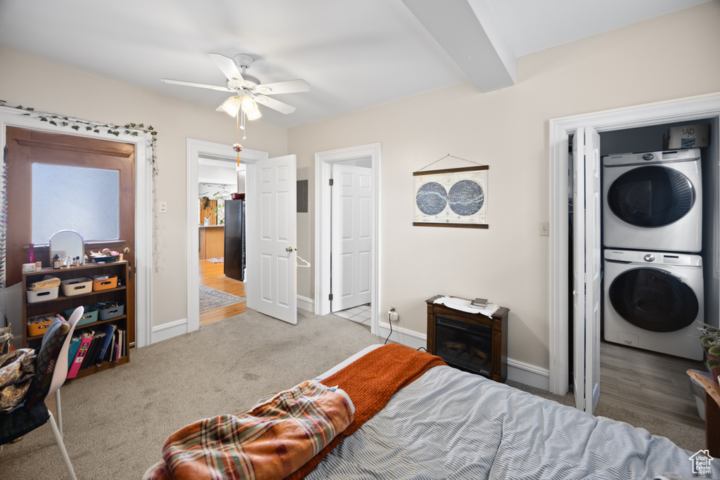 Carpeted bedroom featuring stacked washer / dryer, baseboards, freestanding refrigerator, and a ceiling fan