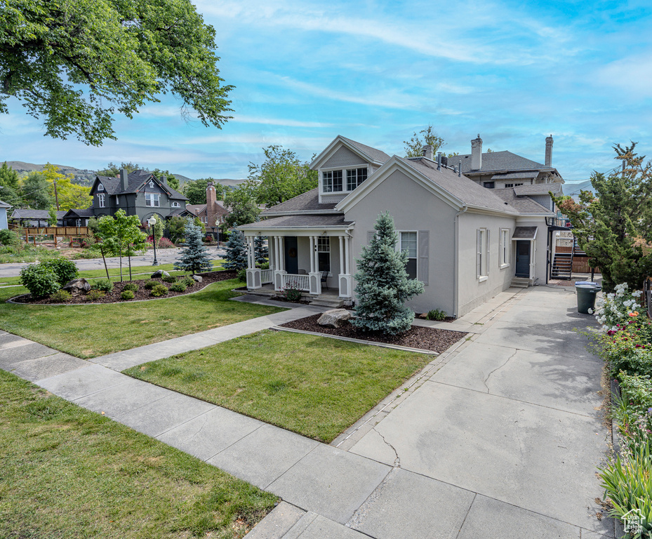 View of front of house with a porch, stucco siding, and roof with shingles