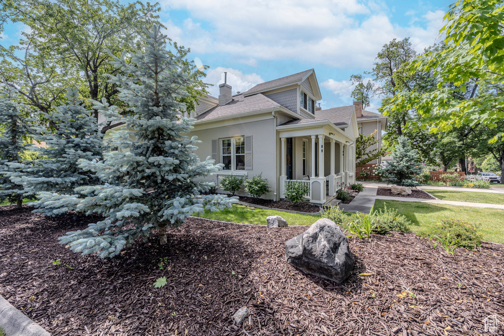 View of side of property with a chimney, stucco siding, a shingled roof, and a lawn